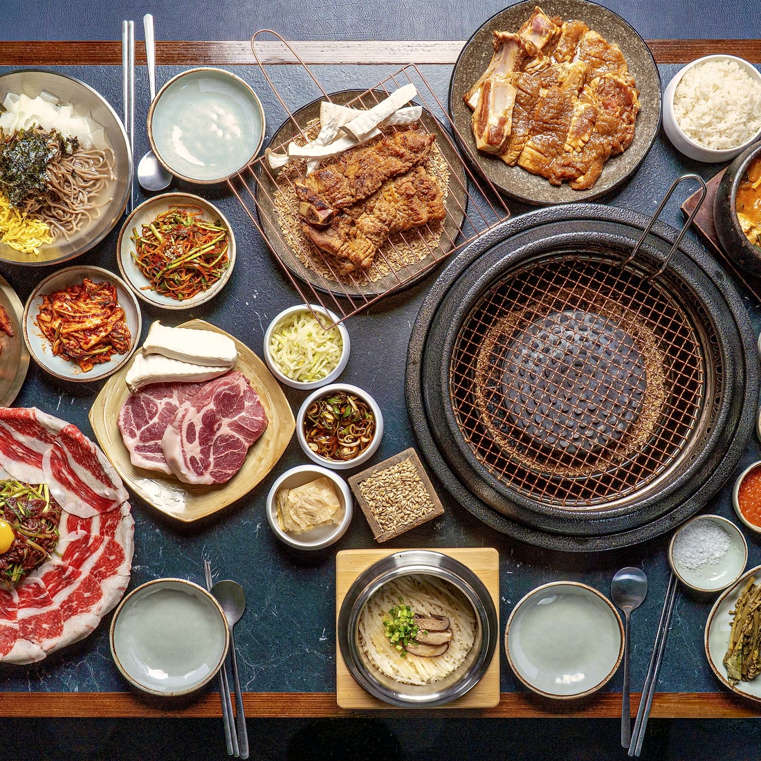 산솔 신사본점 대표 한 상 — 무쇠 불판 위 숙성 돼지구이와 강원식 곁들임, the signature Korean BBQ table (サムギョプサル · 烤肉) of Sansol near Sinsa Station, Seoul